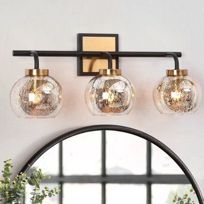 three light vanity fixture with glass globes and brass accents in an elegant bathroom setting