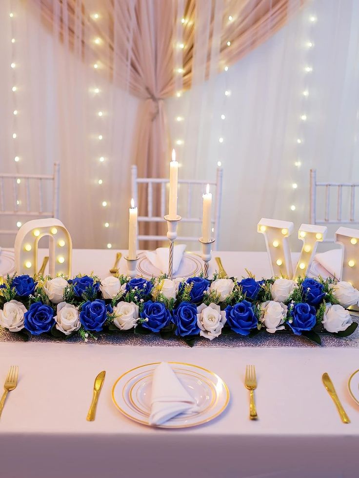 the table is set with blue and white flowers, gold cutlery, and candles