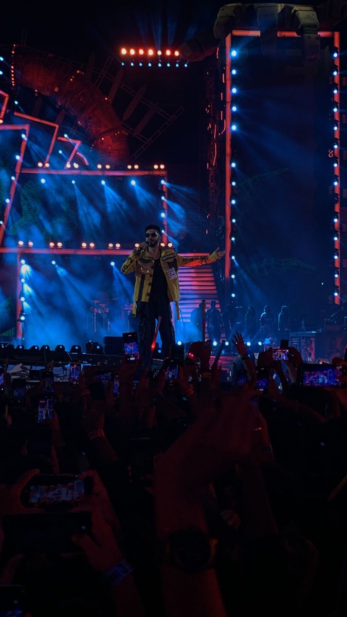 a man standing on top of a stage holding his arms up in front of him