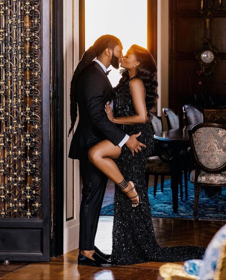 a man and woman in formal wear kissing each other on the cheek while standing next to an open door