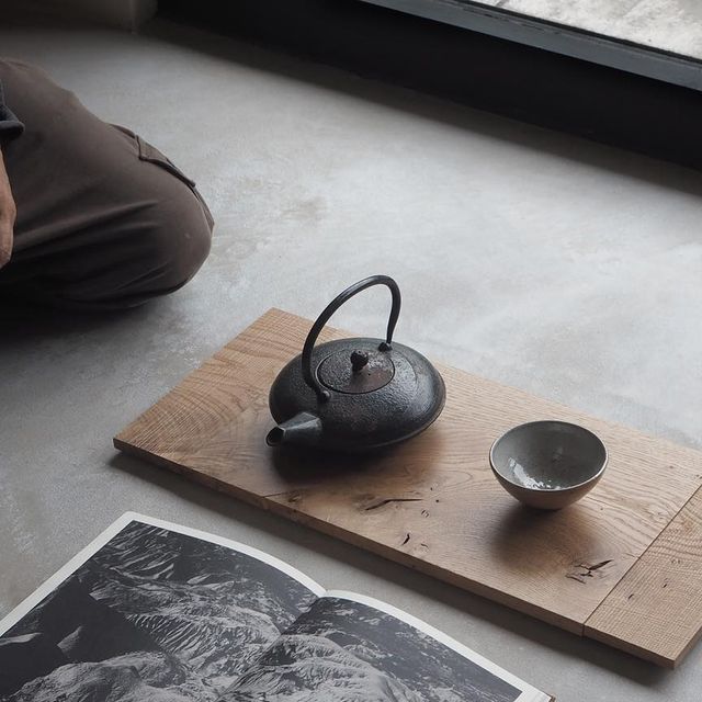 a tea pot sitting on top of a wooden tray next to a black and white photo