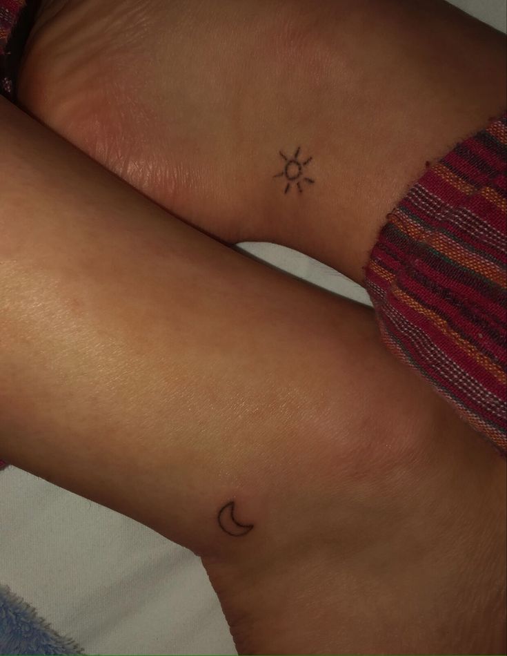 two people with tattoos on their legs, one has a sun and the other is a moon