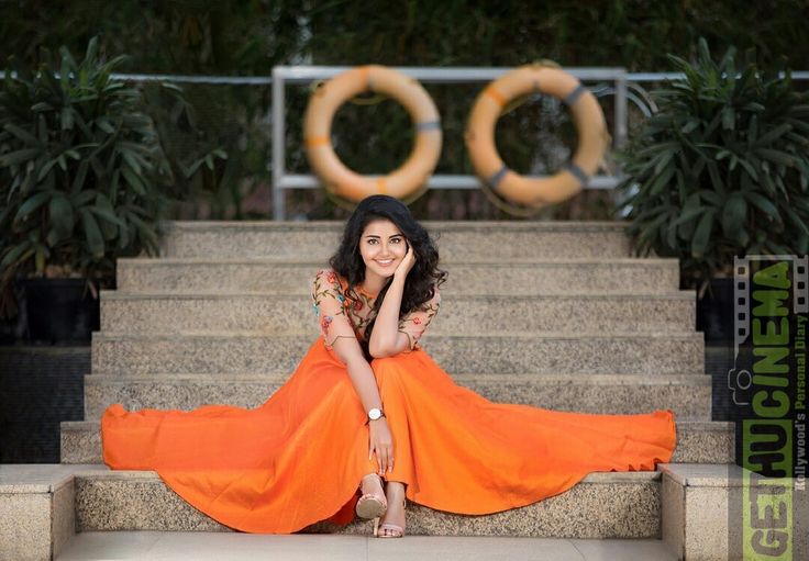 a woman in an orange dress sitting on some steps