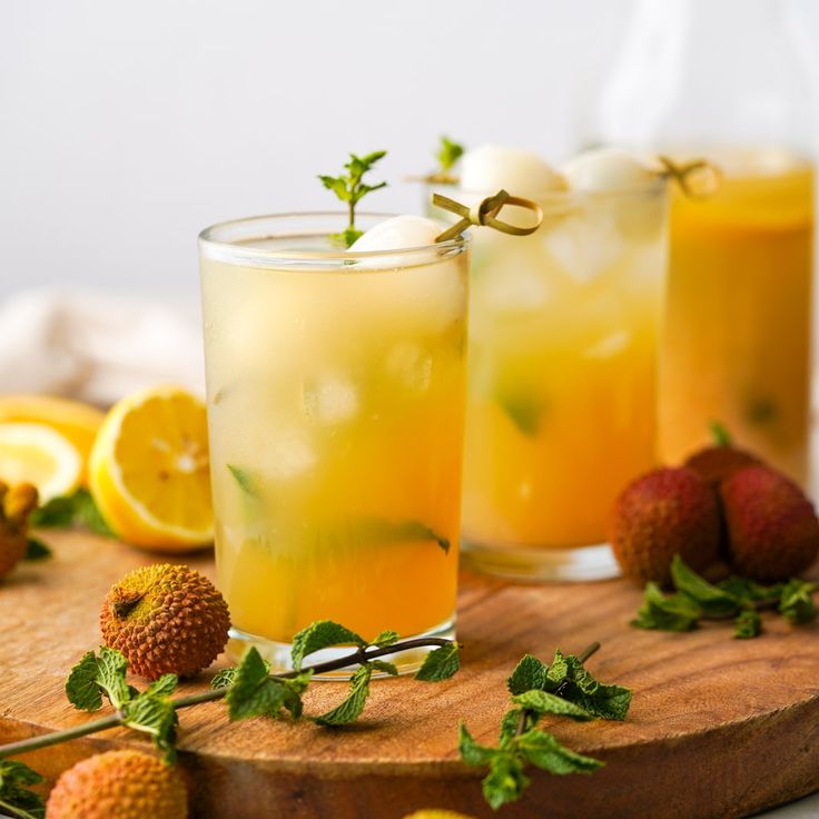 two glasses filled with lemonade and strawberries on a cutting board