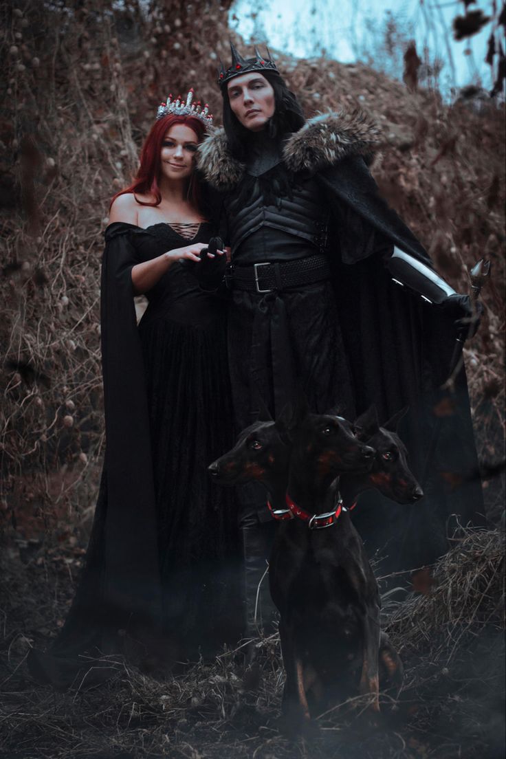 a man and woman dressed up in black standing next to a dog wearing a crown