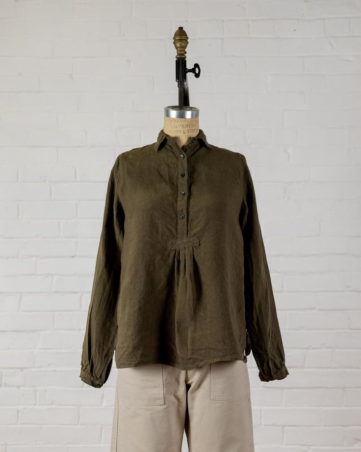 Long sleeve top with a small collar to wear up or down, mother of pearl button front and cuffs. Small gather at bottom of button front. Easy to wear on it's own, or layered under another top, jacket or sweater.  100% Linen. Made in the U.S.A. All of our pieces have been pre washed and dried to minimize any shrinkage. W Winter Cotton Blouse With Buttons, Relaxed Fit Tops With Fold Down Collar And Placket, Relaxed Fit Tops With Placket And Fold Down Collar, Classic Tops With Buttons For Layering, Cotton Tops With Cuffed Sleeves For Fall, Fall Cotton Tops With Cuffed Sleeves, Casual Long Sleeve Top With Smocked Cuffs, Fall Workwear Tops With Smocked Cuffs, Classic Fall Tops With Placket