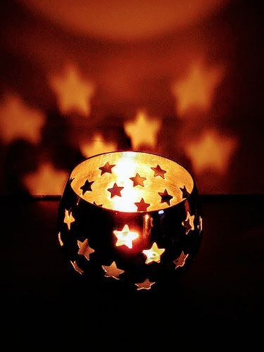 a lit candle with stars on it sitting in front of a dark wall and floor