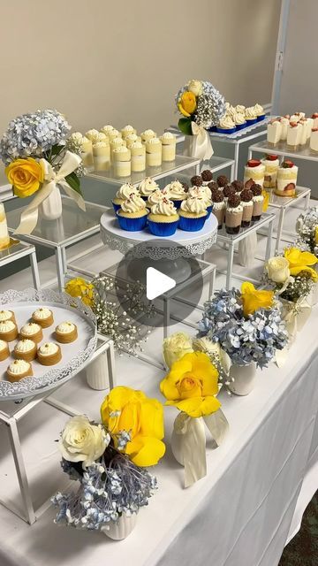 a table topped with cakes and cupcakes covered in frosting on top of a white table cloth