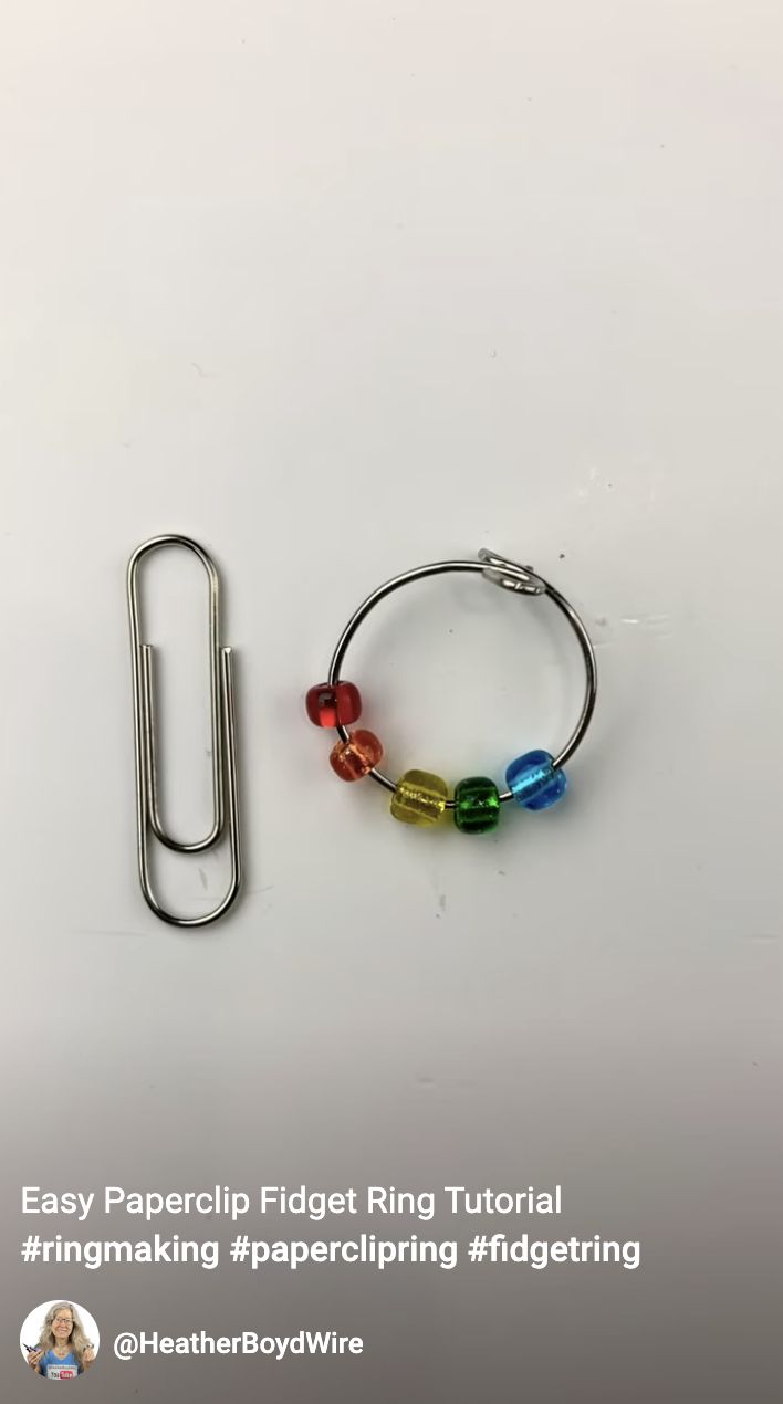 a paper clip and some colorful beads on a white surface with the words easy paperclip fidget ring