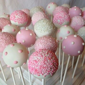 pink and white cake pops with sprinkles on them sitting on a table