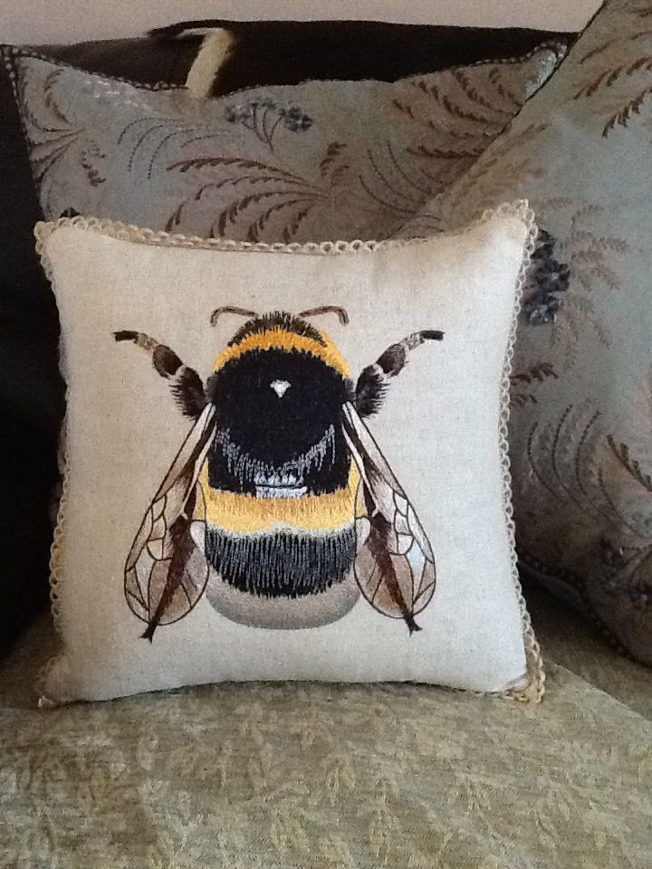 a close up of a pillow on a couch with a bee embroidered on the front