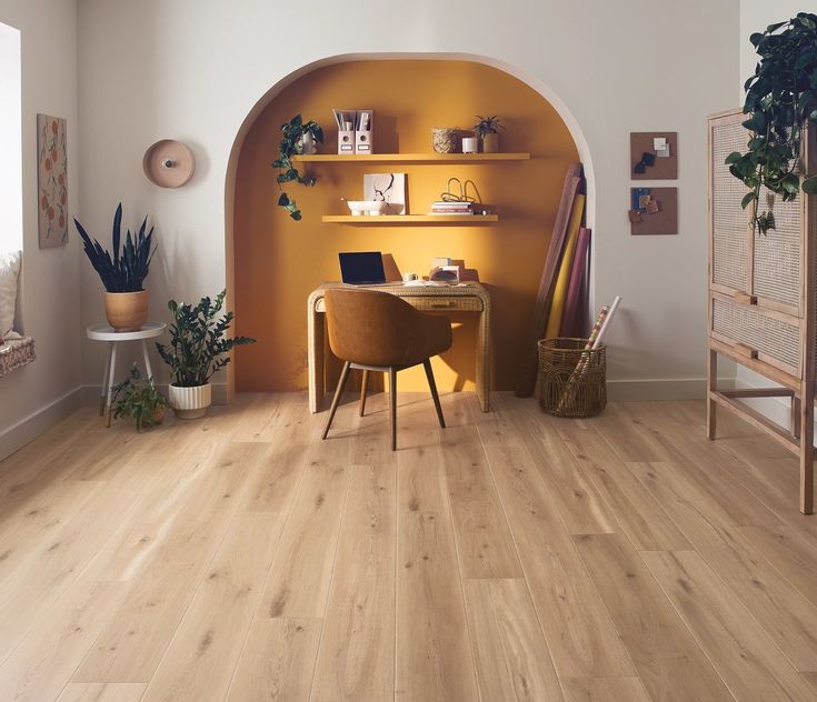 a room with wood floors and yellow walls is pictured in this image, there are plants on the shelves