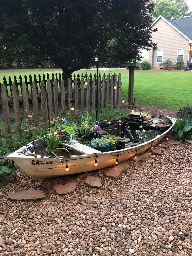 a boat that is sitting in the gravel near a fence and some lights on it