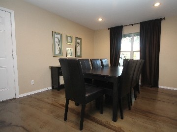 a dining room table with black chairs and pictures on the wall