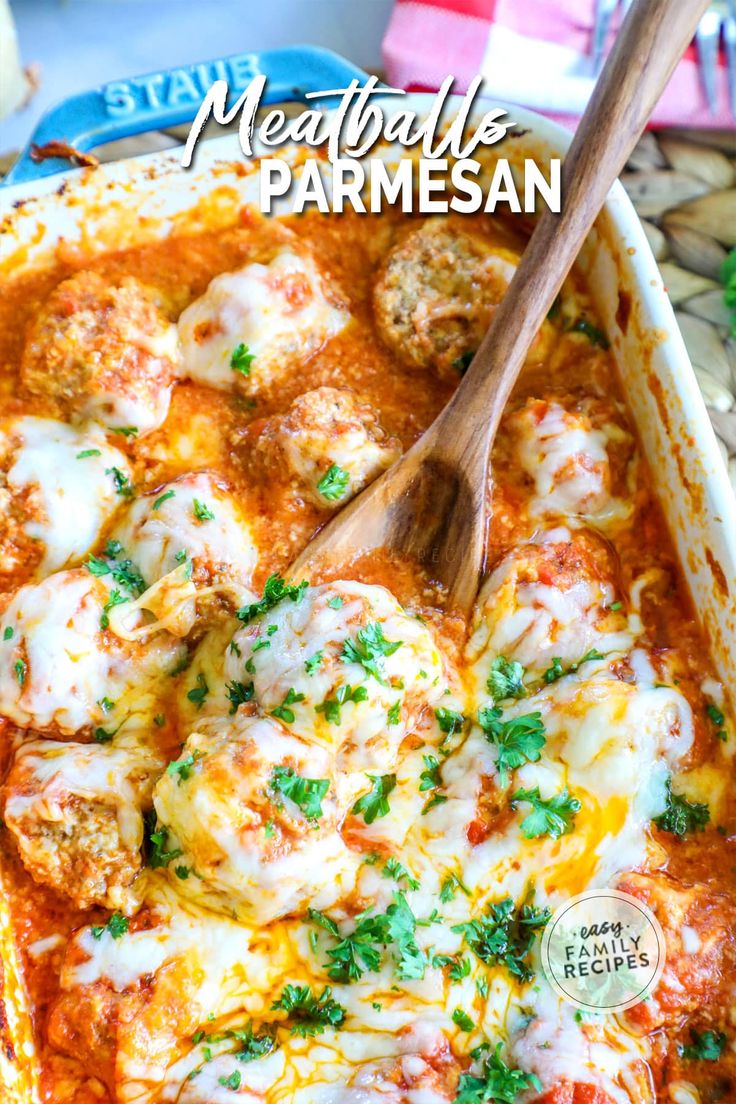 meatballs and parmesan in a casserole dish with a wooden spoon