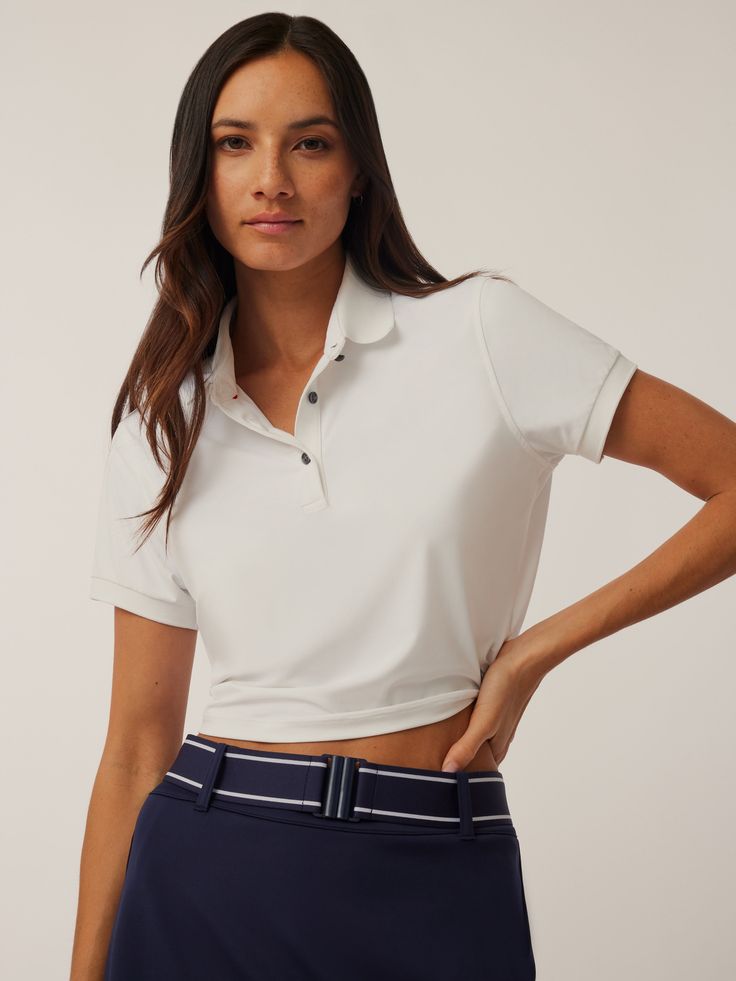 The Cropped Scarlett Polo is designed to elevate every aspect of your life. Designed with an athletic cropped fit to provide high performance and comfort. Featuring a signature knit collar with contrast tipping and a three-button placket. Finished with ribbed cuffs and hem band. Fitted Athleisure Tops For Workwear, Fitted Classic Tops With Contrast Trim, Athleisure Sports Top With Polo Collar, Fitted Tops With Ribbed Collar For Golf, Sporty Stretch Tops For Work, Fitted Athleisure Activewear With Contrast Trim, Classic Fitted Go-dry Tops, White Activewear With Contrast Trim For Sports, Sporty White Activewear For Golf