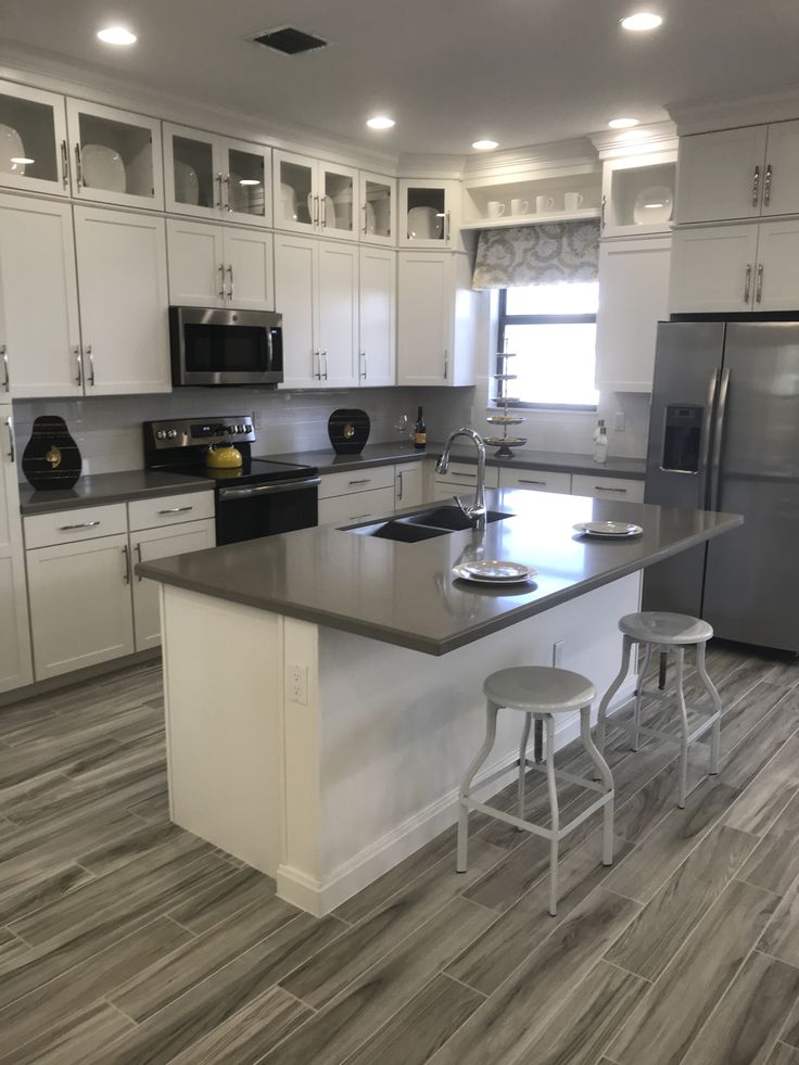 a large kitchen with white cabinets and stainless steel appliances on the counter top, along with two bar stools