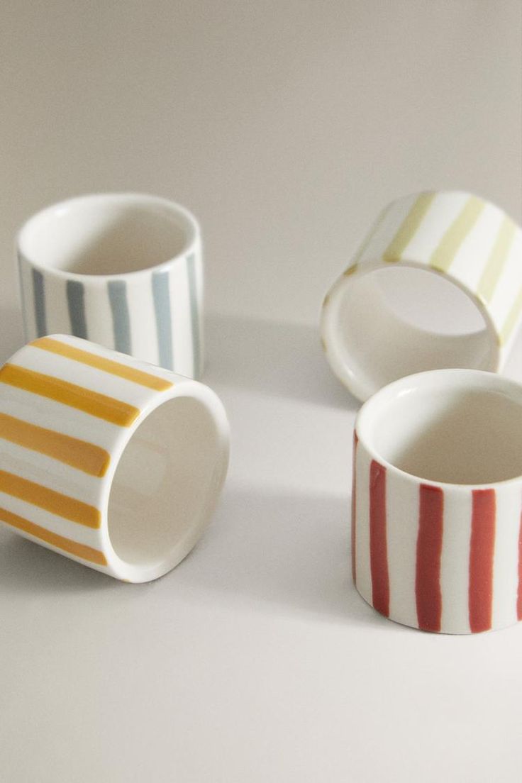 three striped cups sitting next to each other on a white counter top, with one empty cup in the middle