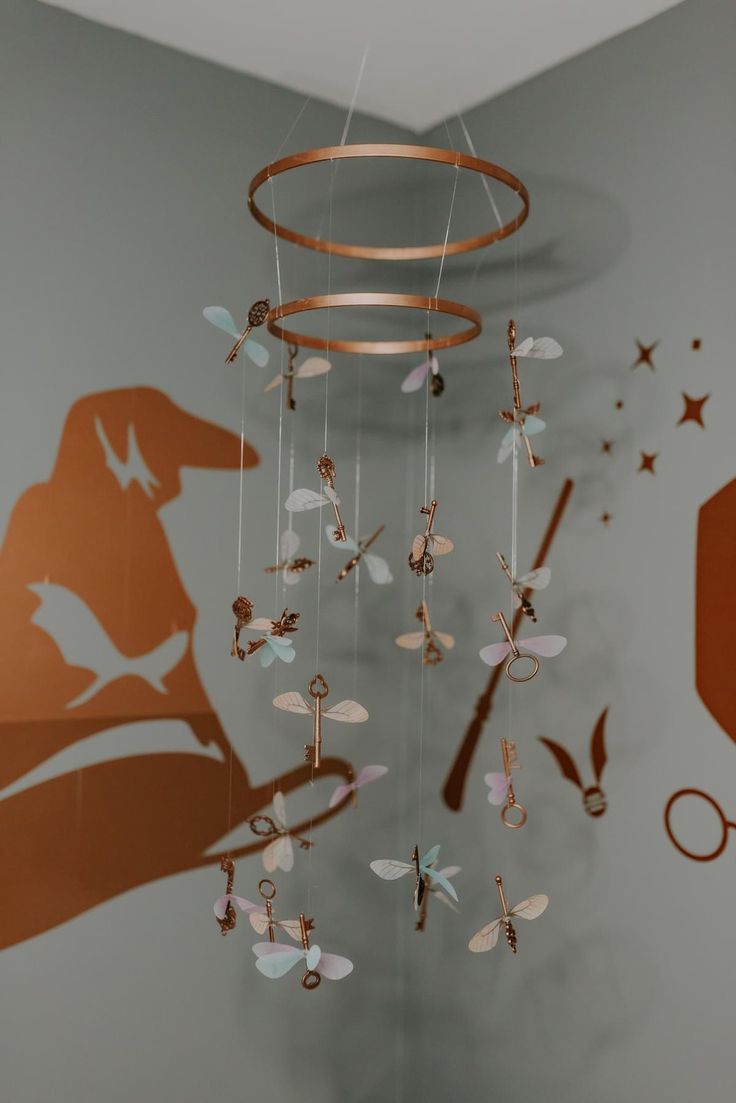 a wind chime hanging from the ceiling in front of a wall with scissors and stars