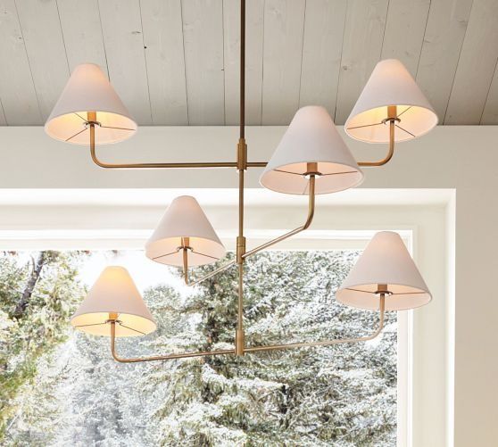 a chandelier hanging from the ceiling in front of a window with trees outside