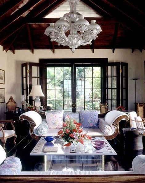 a living room filled with lots of furniture and a chandelier hanging from the ceiling