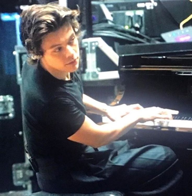 a young man sitting at a piano playing the keyboard