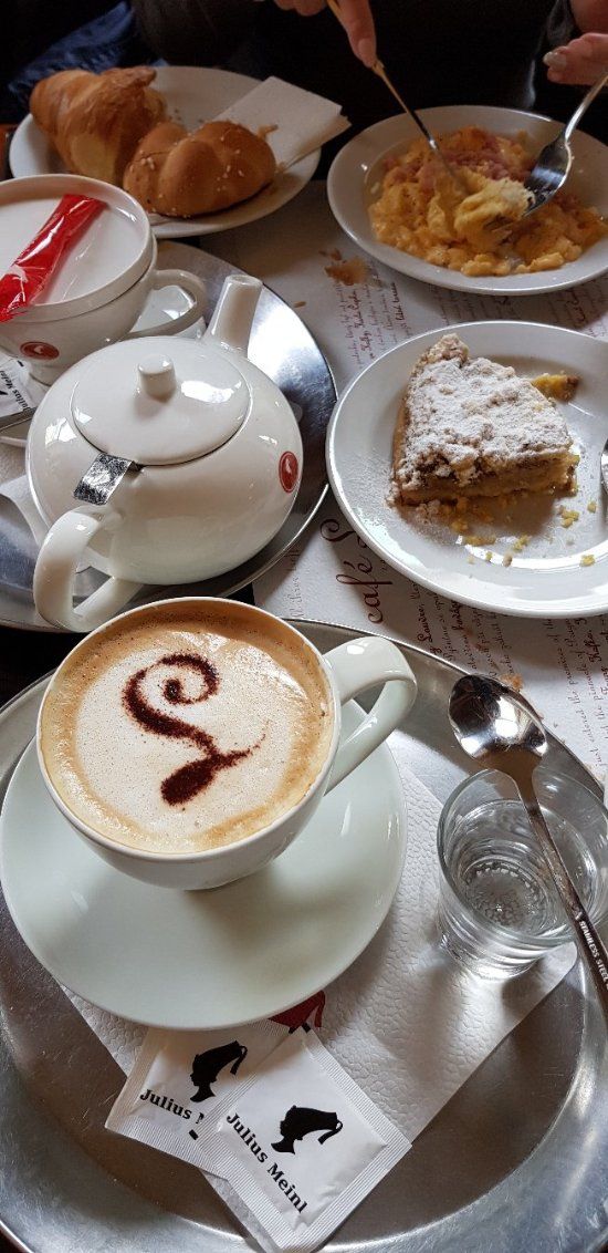 a table topped with plates and cups filled with desserts next to pastry on top of each other