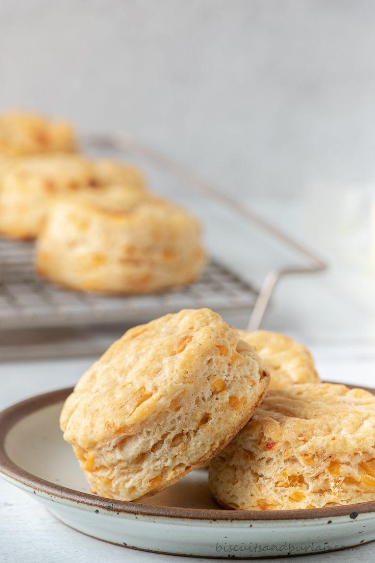 three biscuits on a plate next to a cooling rack with more biscuits in the background