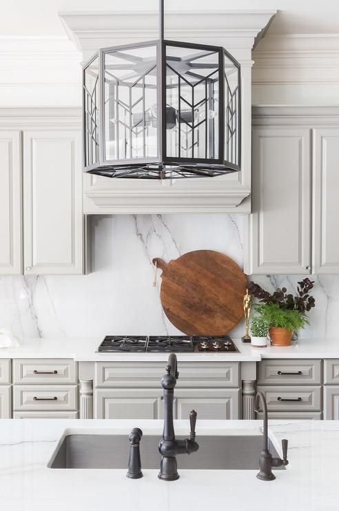 a kitchen with white cabinets and marble counter tops, an island in the middle has a wooden cutting board on it