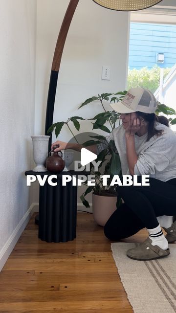 a woman sitting on the floor next to a potted plant