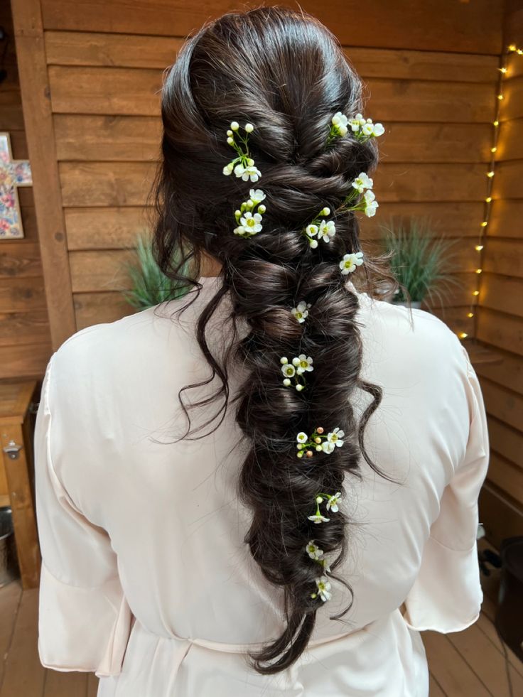 the back of a woman's head with long hair and flowers in her hair