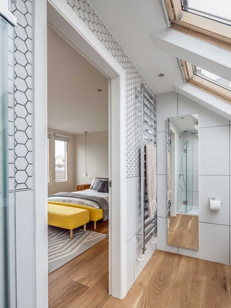 an attic bedroom with skylights and white walls, hardwood floors, and a yellow bed