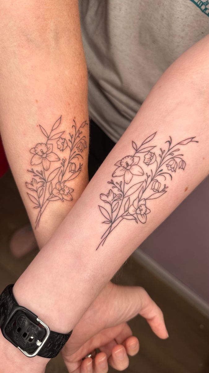 two people holding hands with tattoos on their arms