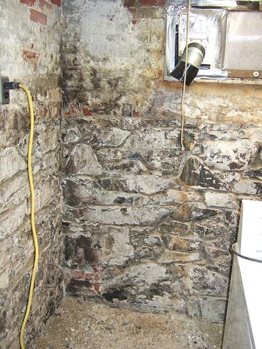 an old brick wall with a water heater in the corner