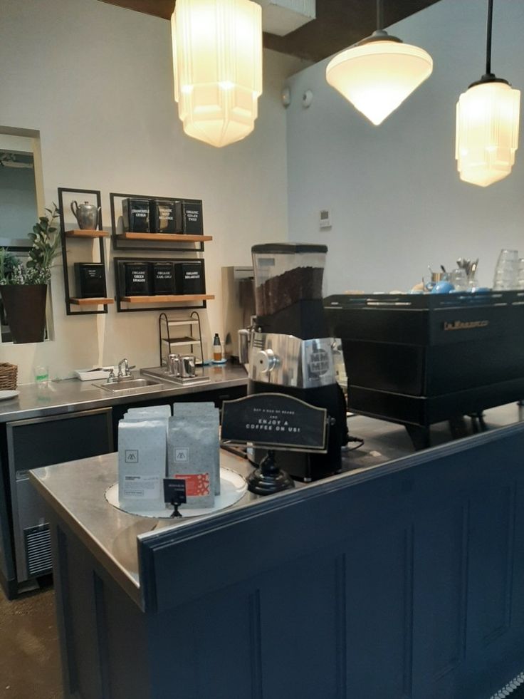 an empty coffee shop with lots of counter space and lights hanging from the ceiling above it