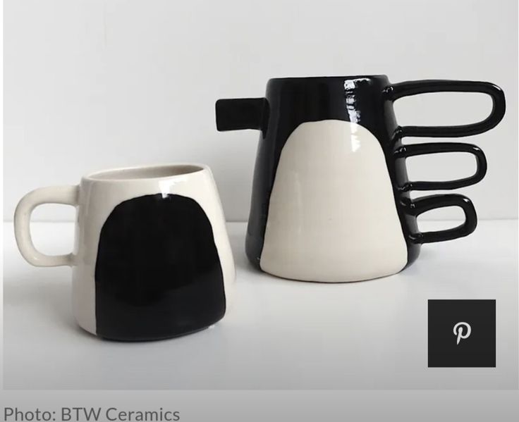 two black and white coffee mugs sitting next to each other