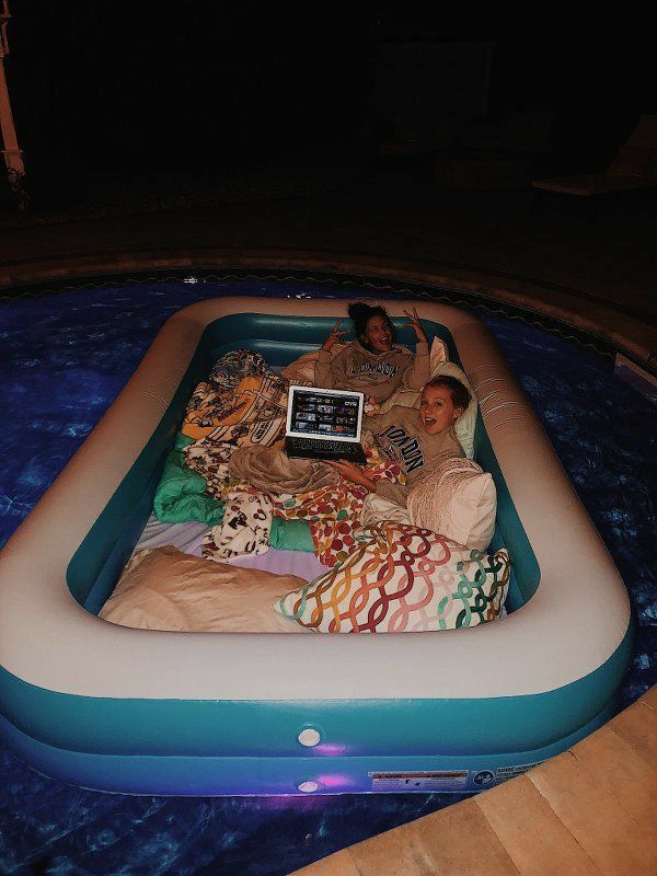 two people laying in an inflatable pool with a laptop