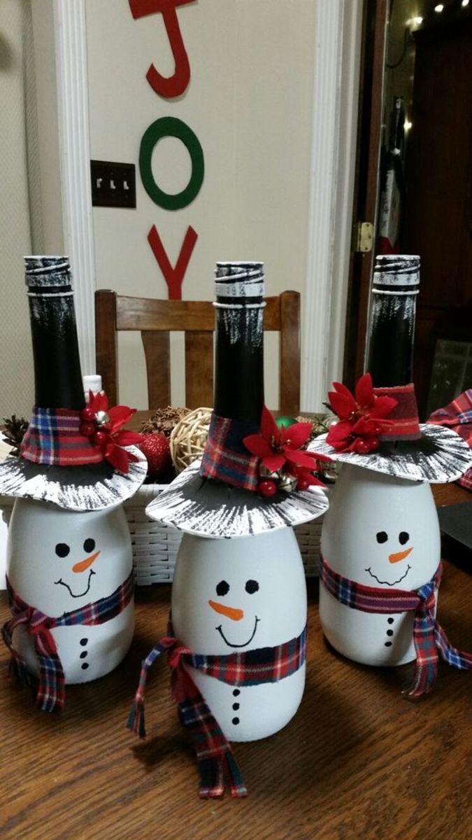 three snowmen with hats and scarfs on sitting in front of a christmas decoration