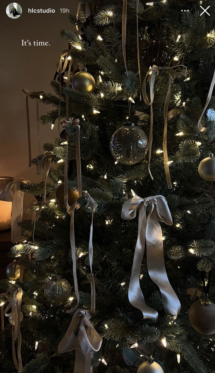 a christmas tree with ornaments and lights on it's branches is decorated in gold, silver and white