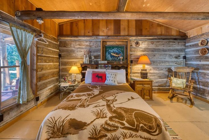 a bed in a room with wooden walls and ceiling