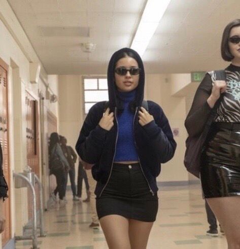 two women walking down a hallway wearing short skirts and high heeled boots with sunglasses on