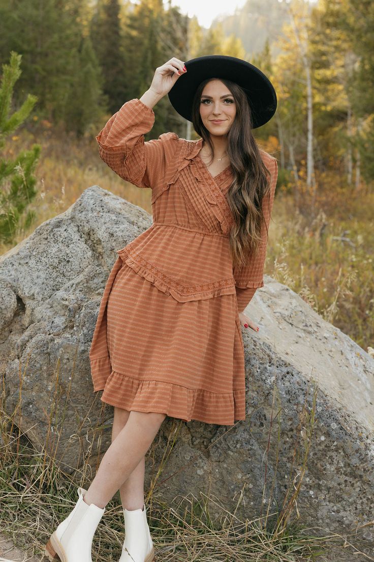 Add a touch of whimsy to your wardrobe with the Libbie Dress-Rust. This knee length dress features pleated detail on the chest and sleeves, along with a v-neckline adorned with embroidered lace. The long sleeves provide coverage while still showcasing the stunning design. Perfect for any occasion, this dress is full of beautiful detail. *Knee length* Material Content: 60% Polyester// 26% Tencel // 14% Spandex // Lining: 100% Rayon Material Pattern: Textured Kirsten is 5'4" wearing a small Model Cottagecore V-neck Dress With Ruffles, Brown V-neck Dress With Ruffle Hem, Casual Fall Midi Dress With Lace Trim, Modest Mid-length Ruffled Dress, Fitted V-neck Cottagecore Dresses, Fall Midi Dress With Lace Trim, Modest Fall Midi Dress With Ruffle Hem, Modest Midi Dress With Ruffle Hem For Fall, Modest Ruffle Hem Midi Dress For Fall