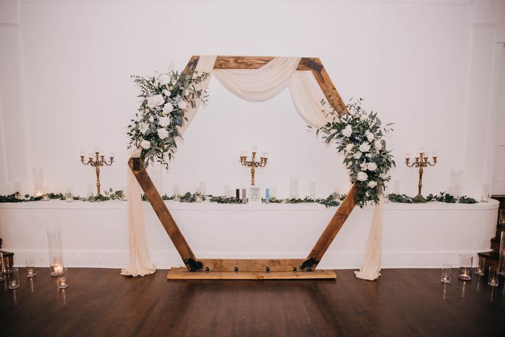 a wedding arch decorated with greenery and candles