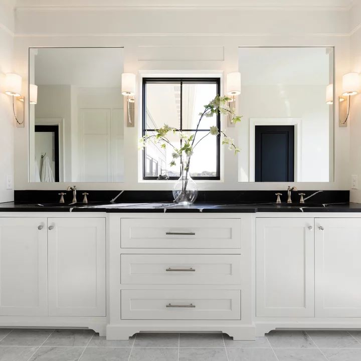 a white bathroom with double sinks and mirrors