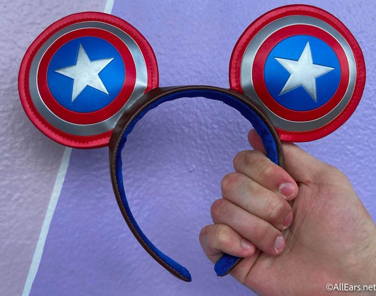 a hand is holding a mickey mouse ears headband with stars on it and red, white, and blue colors