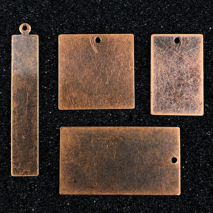 three pieces of metal sitting on top of a black surface with tags attached to them