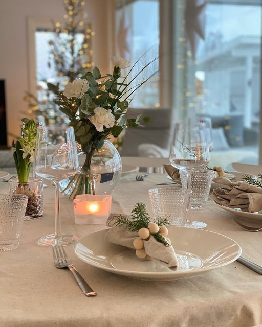 the table is set for dinner with candles and flowers in glass vases on it