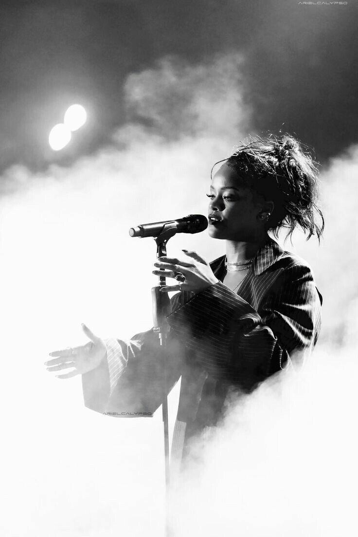 a black and white photo of a woman singing into a microphone