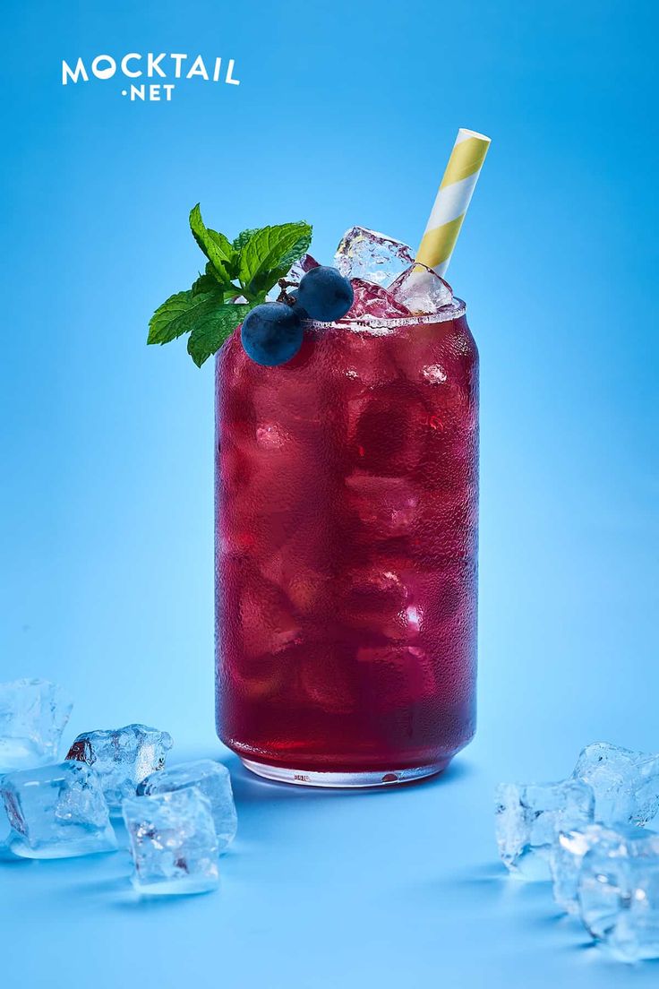 a red drink with ice cubes and a straw garnished with blueberries