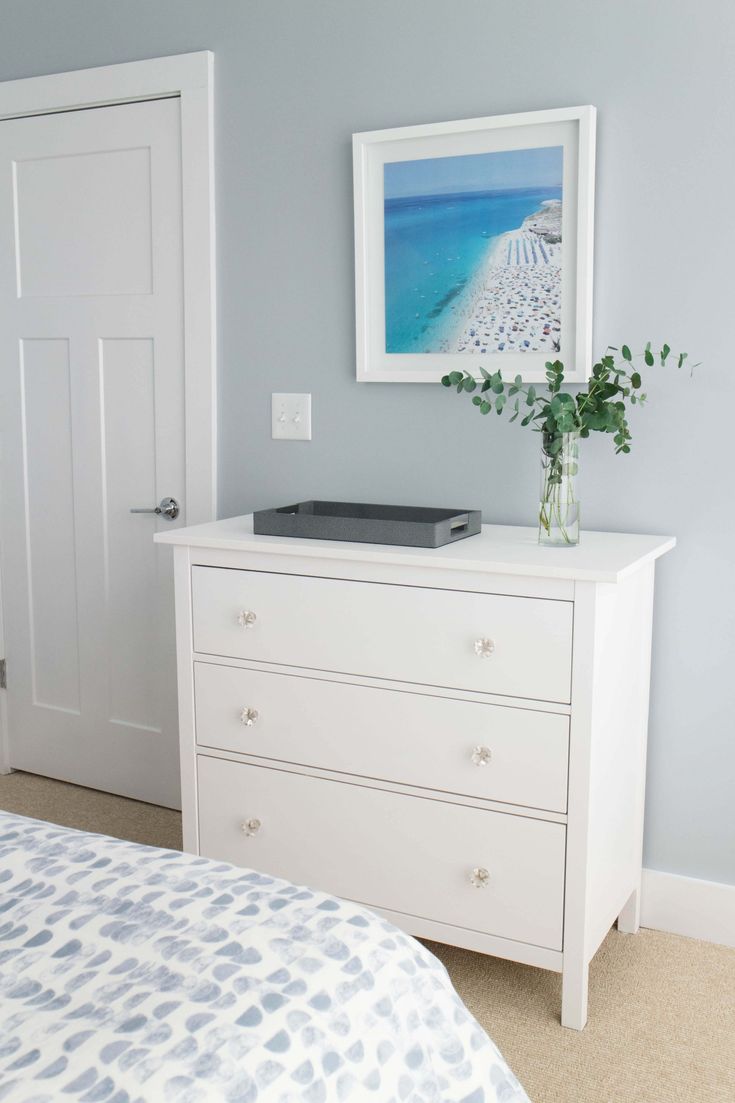 a white dresser sitting next to a bed in a bedroom